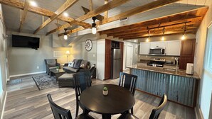 A spacious living area with a dining table, chairs, a sofa, and a kitchen area with modern appliances.