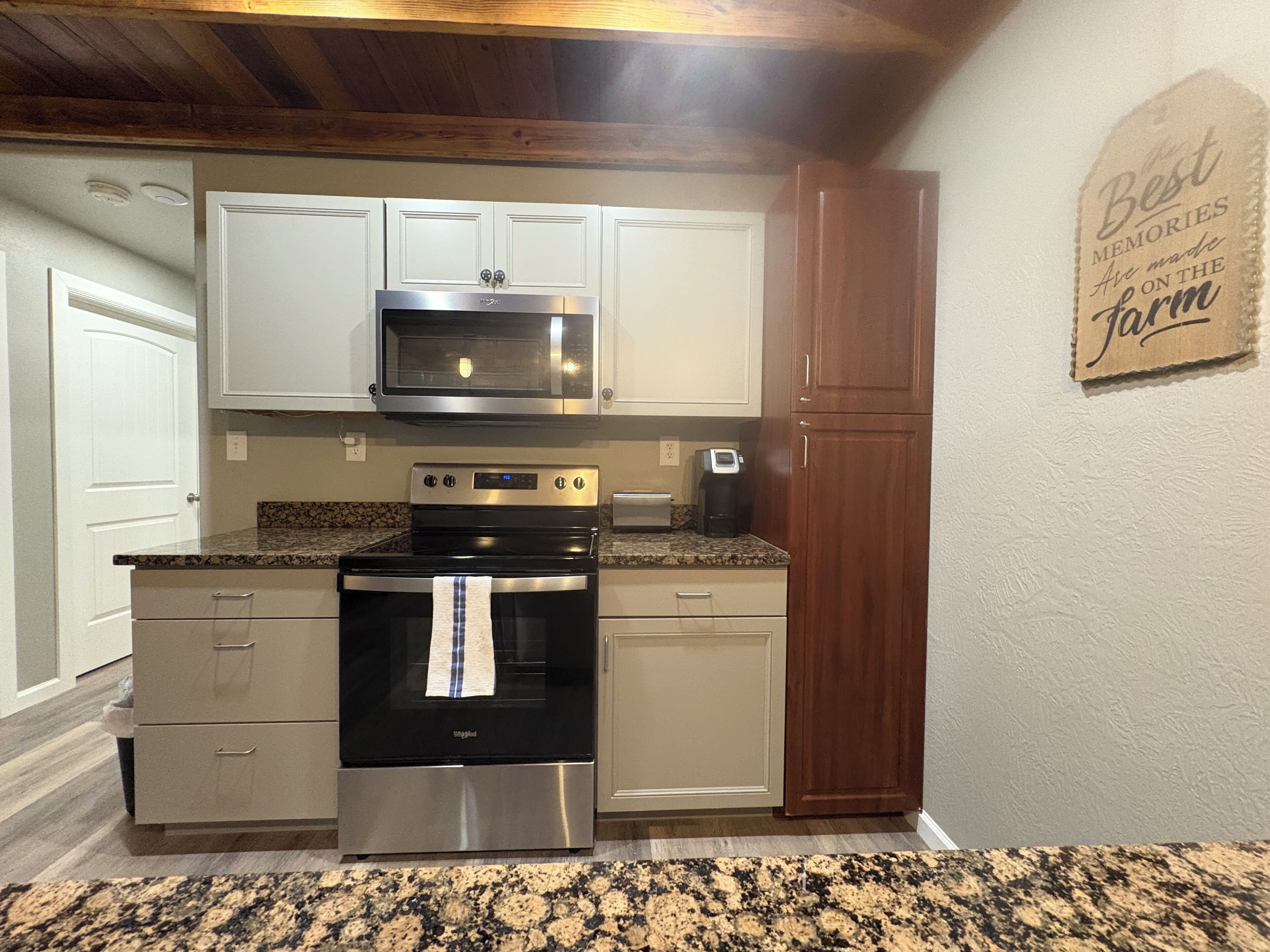 A kitchen with white cabinets, a stainless steel oven, a microwave, and a coffee maker.