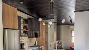 Una cocina moderna con una isla central, electrodomésticos de acero inoxidable y un techo oscuro.