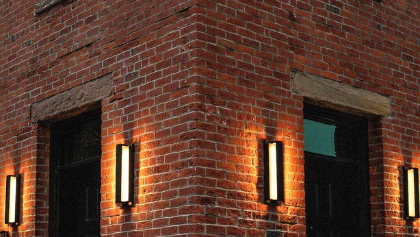 Un edificio de ladrillo con dos entradas iluminadas y un ventanal visible.