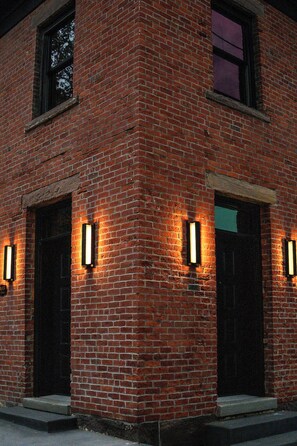 Een bakstenen gebouw met twee verlichte ingangen en een zichtbaar raam.