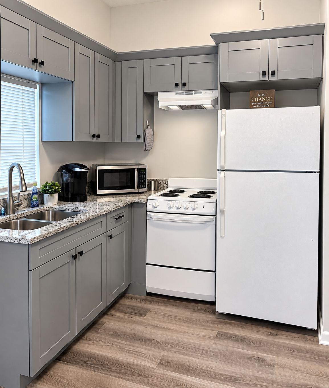 A kitchen with grey cabinets, a white stove, a white refrigerator, and a microwave.