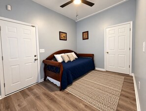 A bedroom with a bed, two doors, a ceiling fan, and a woven rug. - Cozy 2BR Downtown Retreat Just 5 Min to UF Health (Jacksonville)