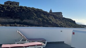 Terraza en la azotea con sillones de descanso y vistas a un edificio histórico en una colina.