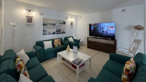 Una sala de estar moderna con sofás verdes, una mesa de centro blanca y un televisor sobre un mueble de madera.