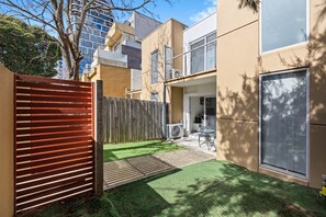 A residential building with a fenced backyard, a patio with outdoor furniture, and a large window. - Sleep 5 | Luxury Box Hill Townhouse (Box Hill)