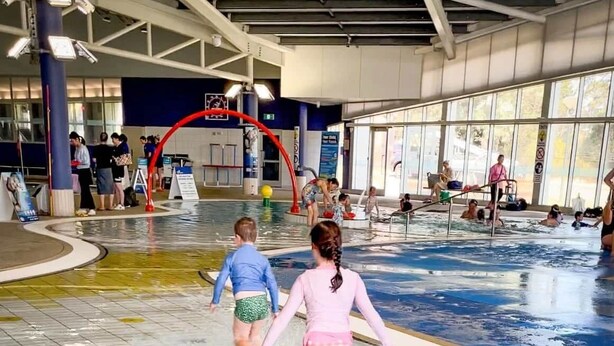 Sisätiloissa sijaitseva uima-allas, jonka pohja on laatoitettu ja jossa on punainen holvikaari.
