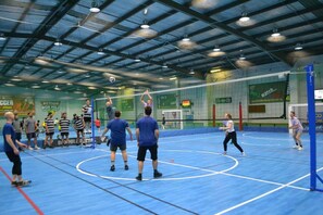 An indoor sports facility with a blue floor, a volleyball net, and spectators. - Sleep 5 | Luxury Box Hill Townhouse (Box Hill)