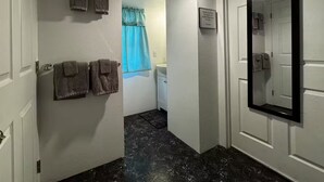 A hallway with a bathroom door, a mirror, and a sign on the wall. - Cozy studio in peaceful Kailua-Kona with refreshing AC (Kailua-Kona)