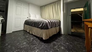 A bedroom with a bed, a wardrobe, a desk, and a door leading to a balcony. - Cozy studio in peaceful Kailua-Kona with refreshing AC (Kailua-Kona)
