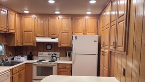 A kitchen with wooden cabinets, a white refrigerator, a stove, and a sink.