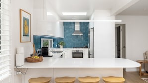 Eine moderne Küche mit einer zentralen Kochinsel, weißen Schränken und einer blauen Spritzschutzwand.