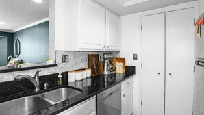 A modern kitchen with a black countertop, white cabinets, and a stainless steel sink. - Stylish Experience in Buckhead (Atlanta)