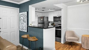 A modern kitchen with white cabinets, a stainless steel refrigerator, and a central island. - Stylish Experience in Buckhead (Atlanta)