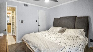 A bedroom with a bed, a ceiling fan, and a door leading to another room. - Stylish Experience in Buckhead (Atlanta)
