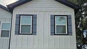 A two-story house with a dark front door, a mailbox, and a small garden with flowers. - The Global Citizen (Pensacola)
