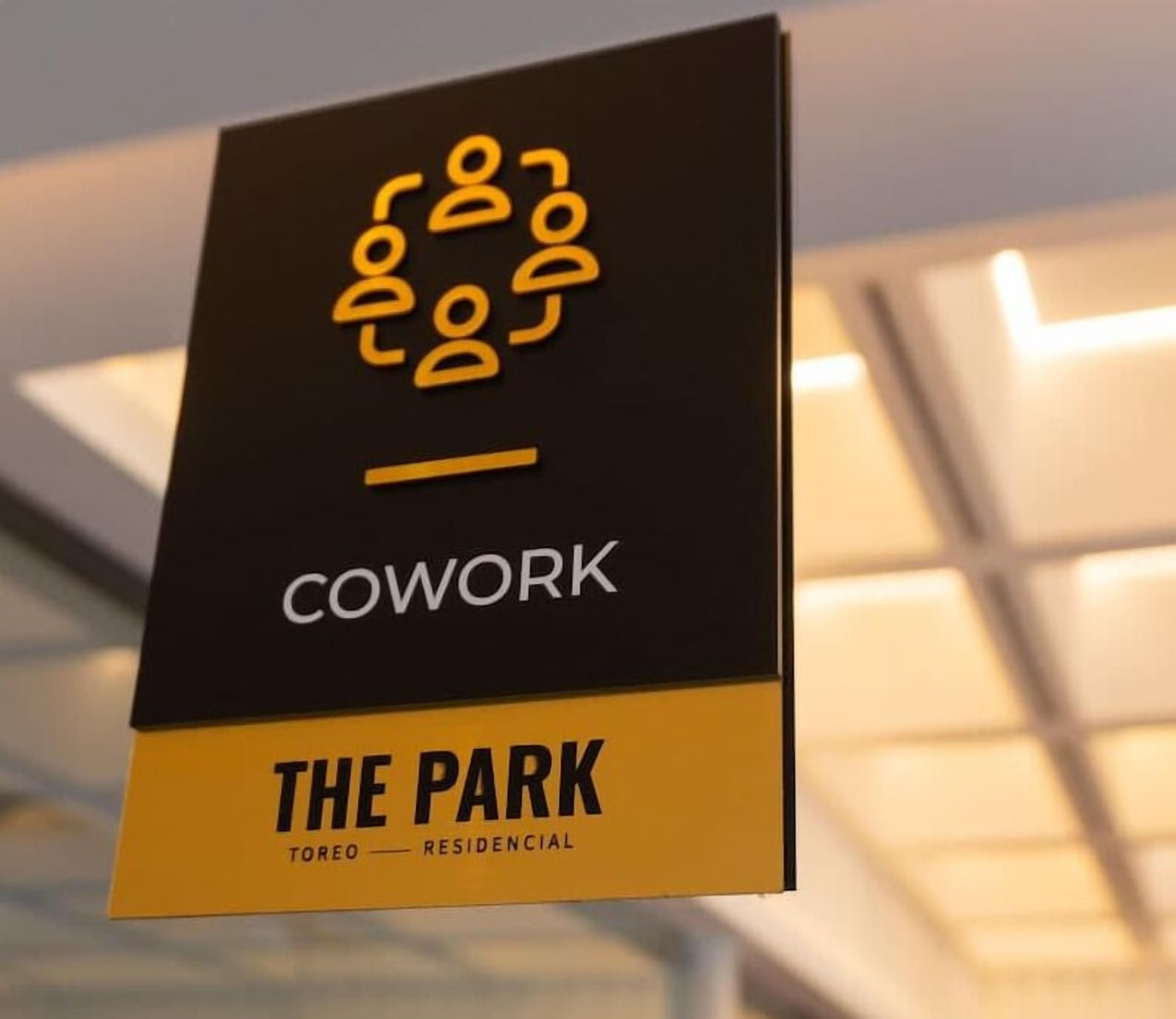Schild für den Coworking Space "The Park" mit einem Logo aus verbundenen Figuren und dem Wort "COWORK".