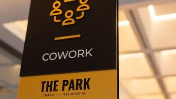 Schild für den Coworking Space "The Park" mit einem Logo aus verbundenen Figuren und dem Wort "COWORK".