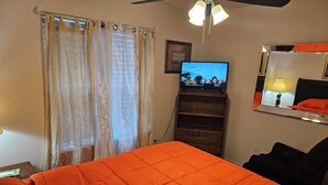 Een hotelkamer met een bed, een televisie, een dressoir en een spiegel.