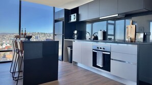 Una cuina moderna amb una illa gran, electrodomèstics d'acer inoxidable i vista a la ciutat.