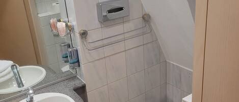 A bathroom with a sink, mirror, toilet, and a towel rack.