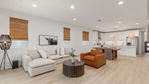Ein modernes Wohnzimmer mit Sofa, Sessel, Couchtisch und Kunstwerk.