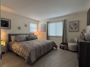 Ein Schlafzimmer mit einem Bett, Nachttischen, einem Sessel und Kunstwerken an den Wänden.