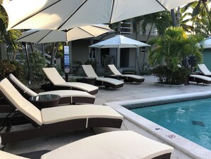 A poolside area with lounge chairs and umbrellas, a pool with a 'No Diving' sign, and a lifeguard warning sign. - EFFICIENCY:  Beautiful Studio, Only Steps Away From Grace Bay Beach and Strip! (GraceBay)