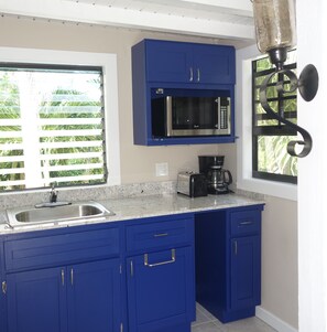 A kitchen with blue cabinets, a stainless steel sink, a microwave, a toaster, and a coffee maker. - EFFICIENCY:  Beautiful Studio, Only Steps Away From Grace Bay Beach and Strip! (GraceBay)