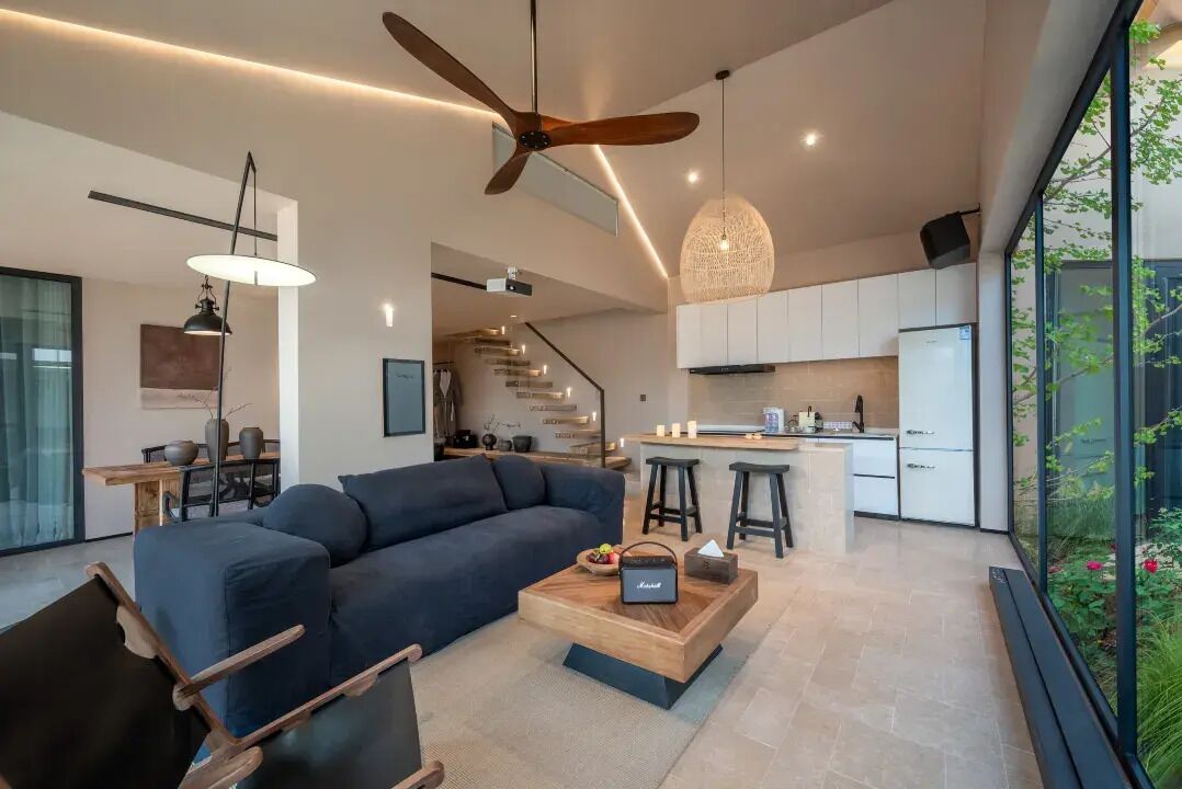 A modern living room with a dark sofa, a wooden coffee table, and a ceiling fan.