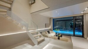 Ein modernes Wohnzimmer mit Treppe, einer Couch und Blick auf einen Swimmingpool.