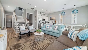 Una sala de estar moderna con una escalera, una cocina y un comedor.