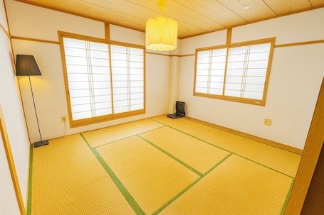 A traditional Japanese room with tatami flooring, sliding doors, and a hanging light fixture.