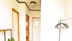 A hallway with a wooden bench, a potted plant, a metal rack, and a door leading to another room. - Lake View Entire House｜Relaxing Private Stay in Nature (Minamikomatsu, Otsu City)