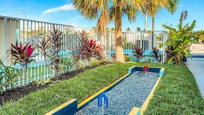 Un jardí amb un planter rectangular, una palmera i una tanca blanca.