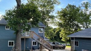 A residential area with two houses, a wooden deck, and a gravel area with outdoor furniture. - 8 miles From IU Campus: Country & Quiet  2-BR apt  in charming Ellettsville (Ellettsville)