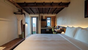 A hotel room with a large bed, a desk, and a kitchenette. - Olwen Boutique Hotel (Da Nang)