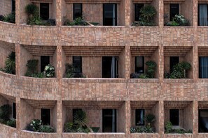 Een meerhoog gebouw met een bakstenen gevel, balkons met planten en meerdere ramen.