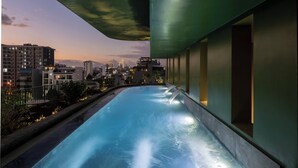 A rooftop pool with a cityscape view, surrounded by modern buildings and a clear sky. - Olwen Boutique Hotel (Da Nang)