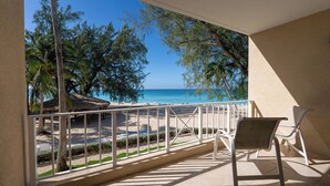A balcony with a view of a beach and palm trees.
