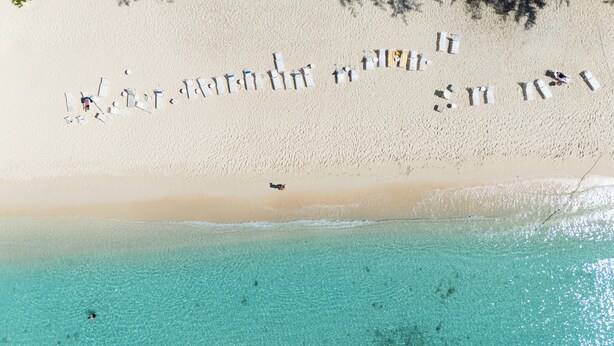 An aerial view of a beach with clear turquoise waters and a sandy shore.