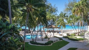 A pool area with palm trees, lounge chairs, and a view of the ocean.