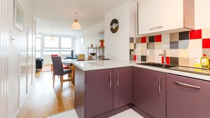 A modern kitchen with a central island, a dining area with a table and chairs, and a view of the living room. - Bright & Spacious 2 Bed Islington Flat | Fast Wi-Fi (London)