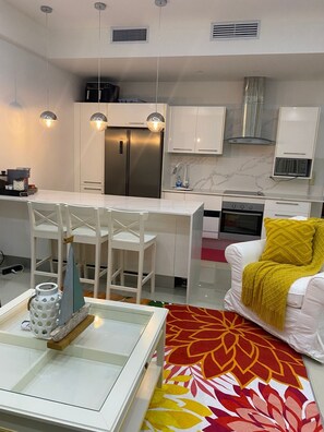 A modern kitchen with white cabinets, stainless steel appliances, and pendant lighting. - Juan Dolio Executive One Bedroom Suite With Ocean Views. (Juan Dolio)