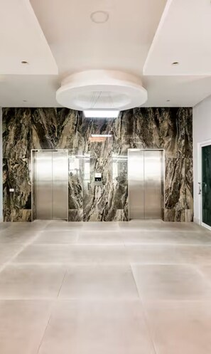 Eine geräumige Lobby mit Marmorwänden, zwei Aufzügen und einem modernen Deckenstil.