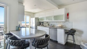 Une cuisine moderne dotée d’un îlot central, de meubles blancs et offrant une vue sur l’extérieur.