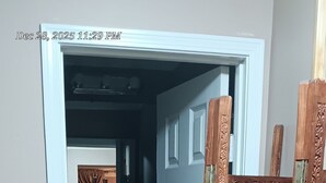 A narrow hallway with a wooden door on the right, leading to a room with a blue carpet and a white door. - Delightful 2-bedroom house with AC in vibrant Newark (Newark)