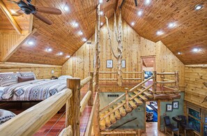 A wooden cabin with a loft bedroom, a staircase, and a dining area. - Luxury Lodge in Hocking Hills, 4 Fireplaces, 12-Person Hot Tub, Secret Game Room (Laurelville)