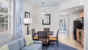 A modern living room with a sofa, dining table, chairs, and a kitchen area with appliances. - Harborside at Atlantis – Premium 2-Bedroom Villa with Full Resort Access (N.P)