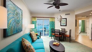 A living room with a teal sofa, a round coffee table, and a dining area with a table and chairs. - Harborside at Atlantis – Premium 2-Bedroom Villa with Full Resort Access (N.P)